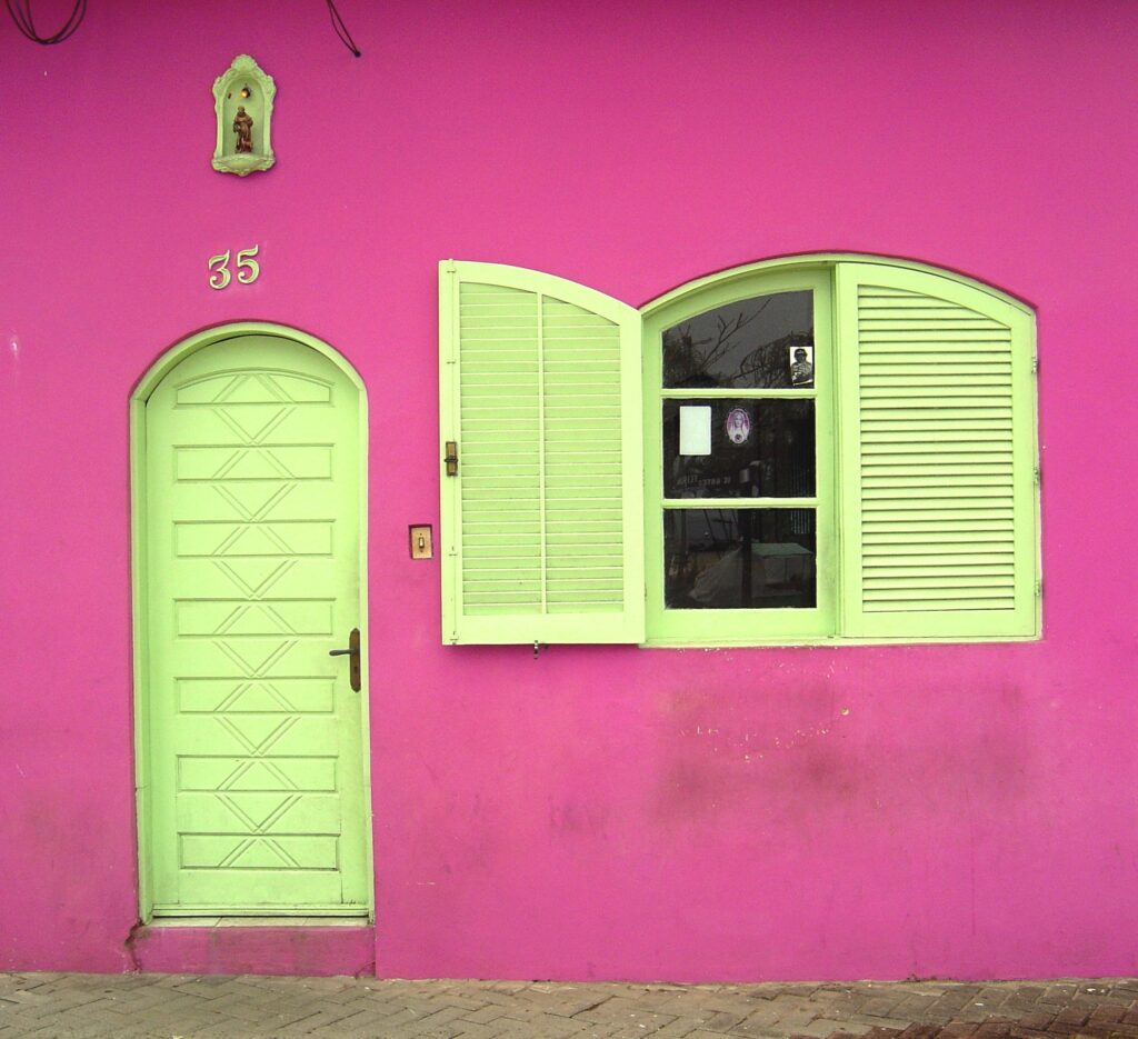 roze gevel met fel gele deur en luiken